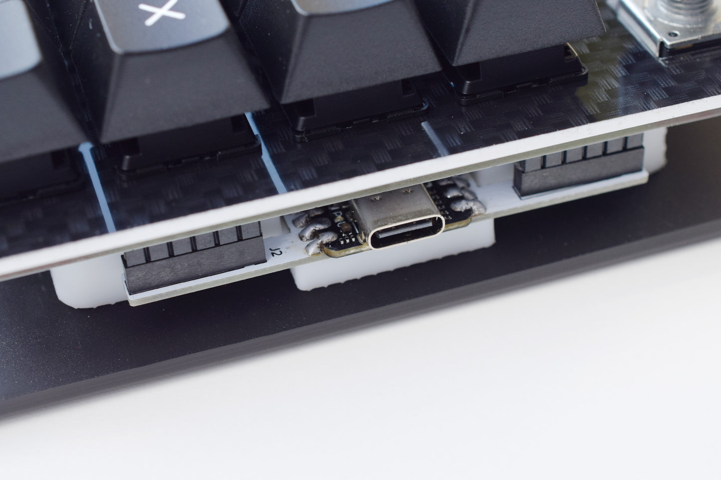 Close-up of a mechanical keyboard with USB cable connection on a white background